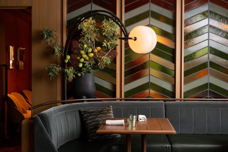 A mohair and leather banquette and custom stained glass in the dining room. Photo: Adahlia Cole.