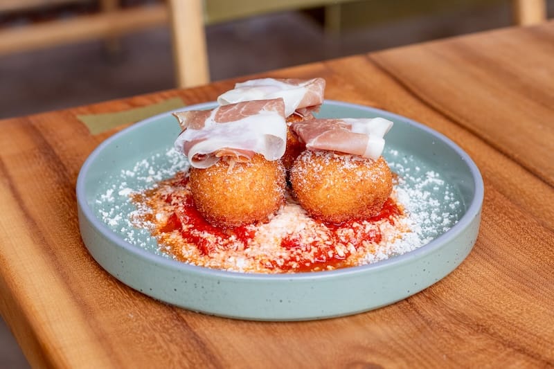Sweet corn arancini topped with a prosciutto add-on. Photo: Isabel Baer.