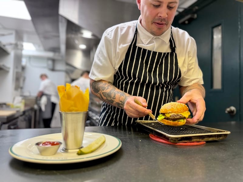 Chef George Dingle plating a burger at the pass. Photo: © tablehopper.com.