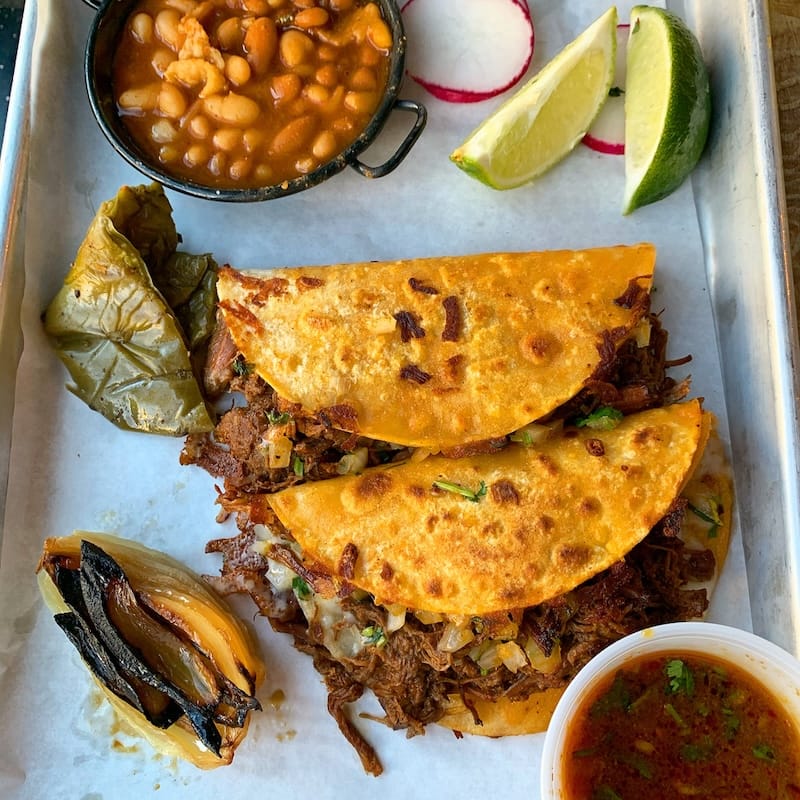 Tacos El Patrón’s signature quesabirria served with nopales, cebolla asada, frijoles, and rabános that come free-of-charge upon request when you get two or more tacos. Photo: © tablehopper.com.