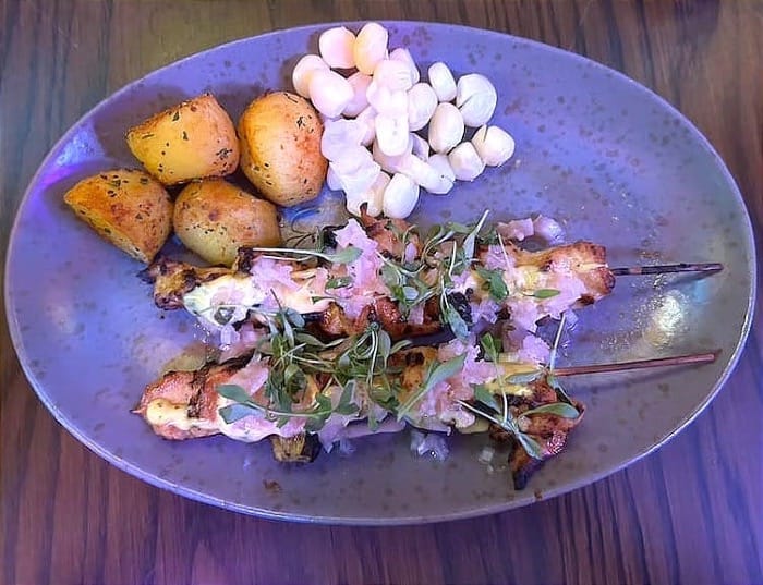 Chicken anticucho garnished with choclo, aji amarillo sauce, and spicy onion relish. Photo: Francesca Gasparini.