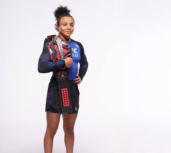 Cassia Moura with a UFC BJJ championship belt over her shoulder