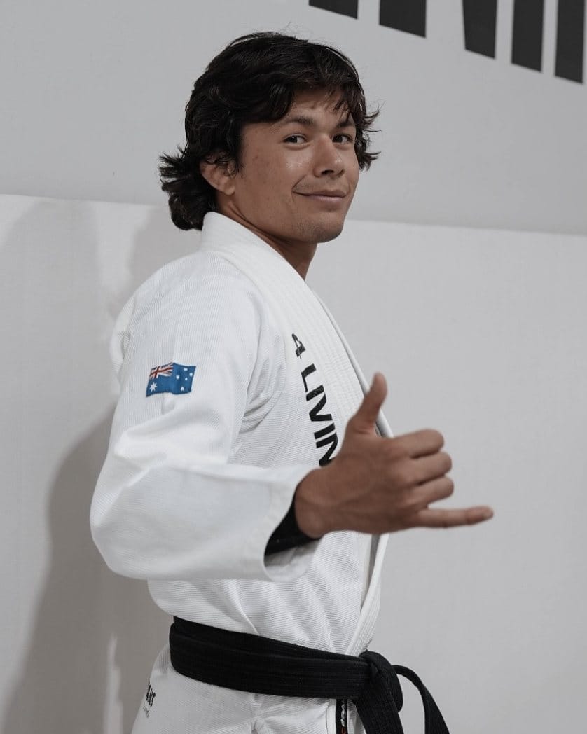 Thalison Soares in a white gi and black belt, smiling and throwing a shaka