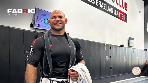 Roberto “Cyborg” Abreu smiling in a Fight Sports rash guard with his black belt over his shoulders, with the Fabric Jiu-Jitsu wordmark
