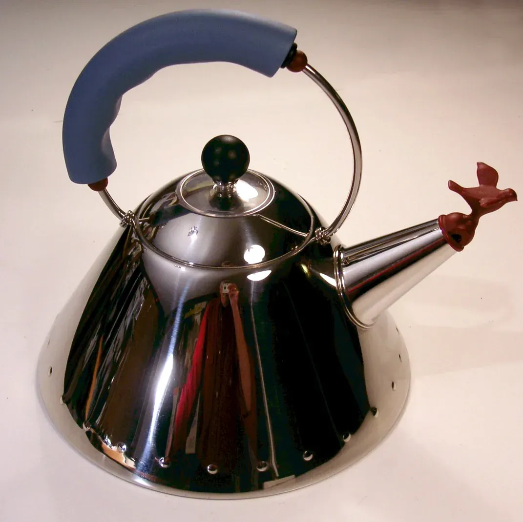 Polished steel Alessi 9093 kettle by Michael Graves with a blue handle and a red bird on the spout