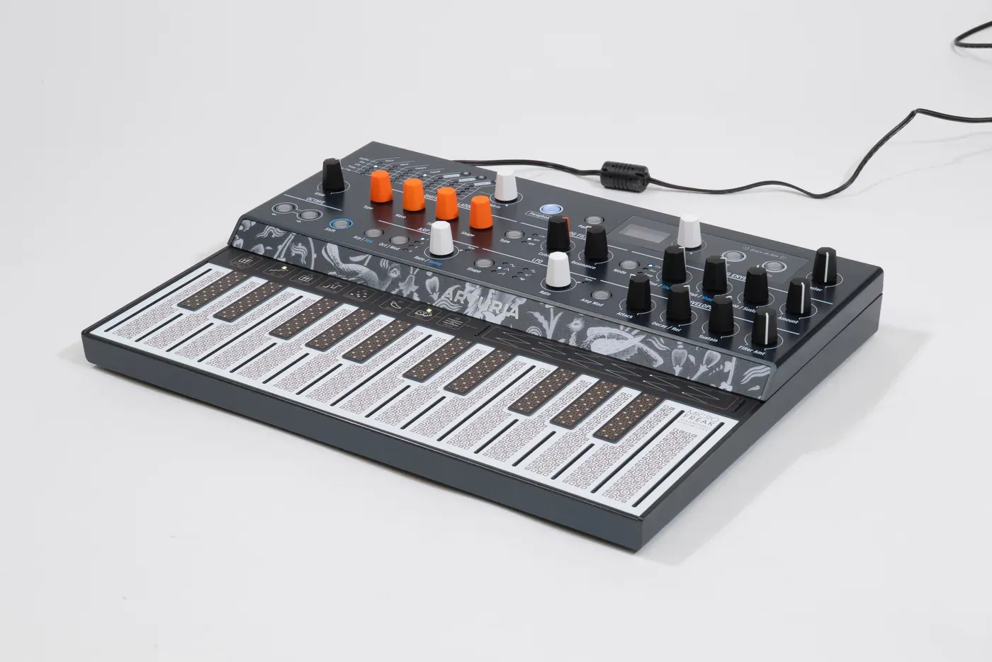 Arturia MicroFreak synthesizer with a flat touch keyboard and orange and white knobs on a white surface