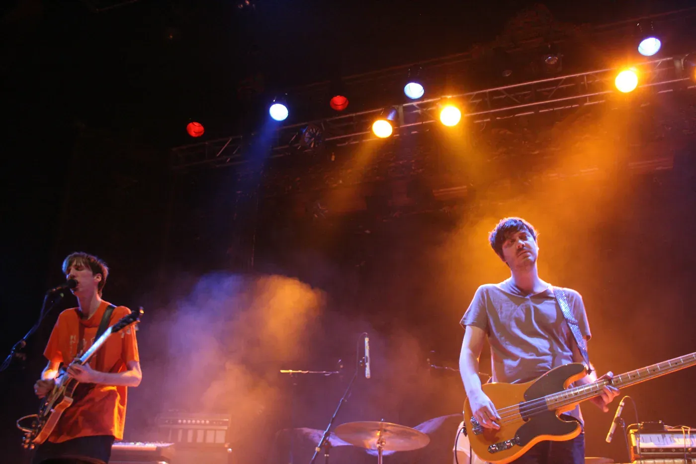 Deerhunter's guitarists performing under orange and blue stage lights at the Ogden Theatre