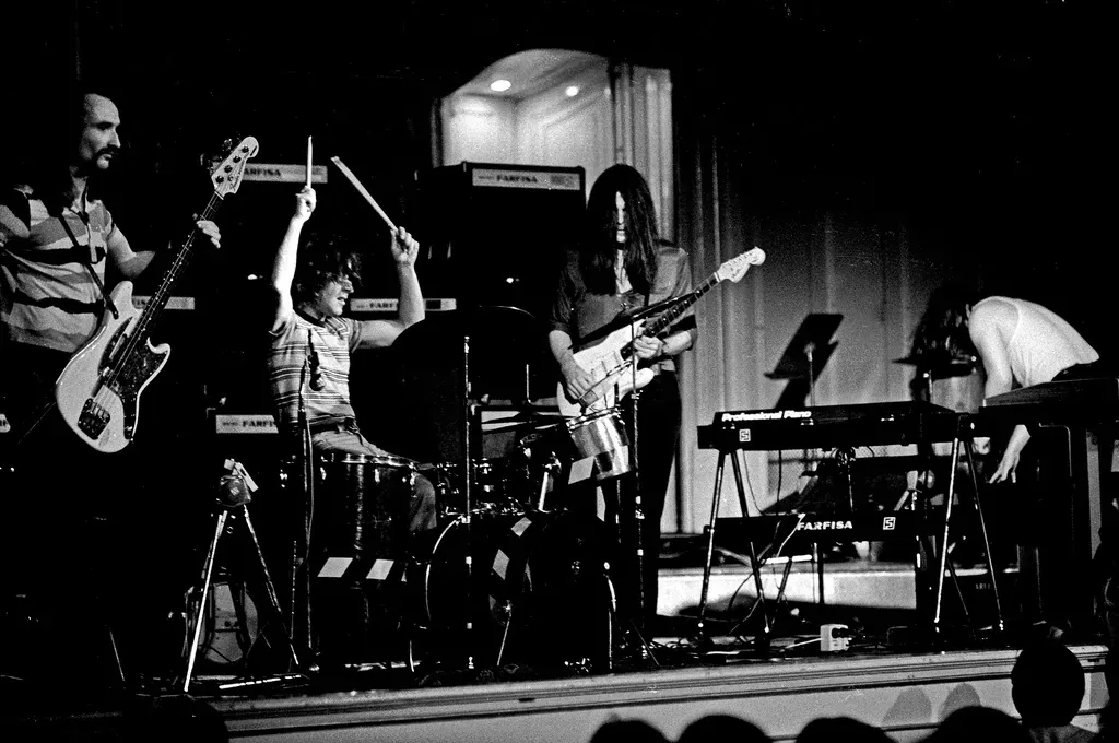 Black and white photo of Can performing on stage in Hamburg in 1972, with guitar, drums and keyboards