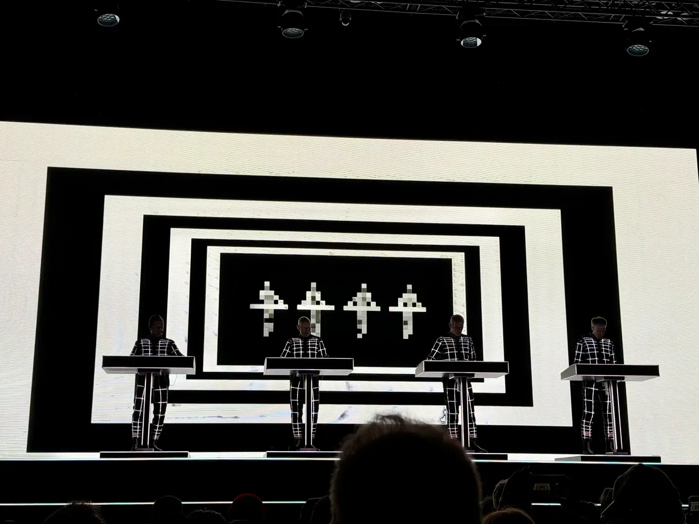 Kraftwerk's four members at their consoles in front of a black and white projection during Autobahn