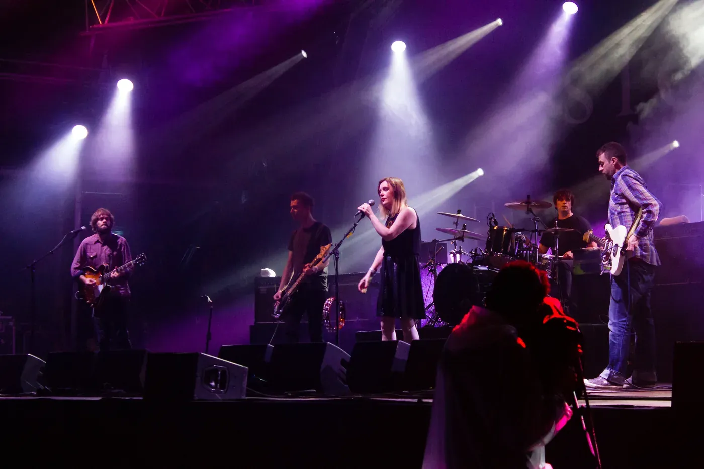Slowdive performing on a festival stage under white and purple spotlights