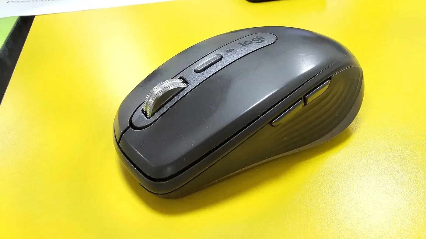 Graphite Logitech MX Anywhere 3 compact wireless mouse on a yellow desk surface