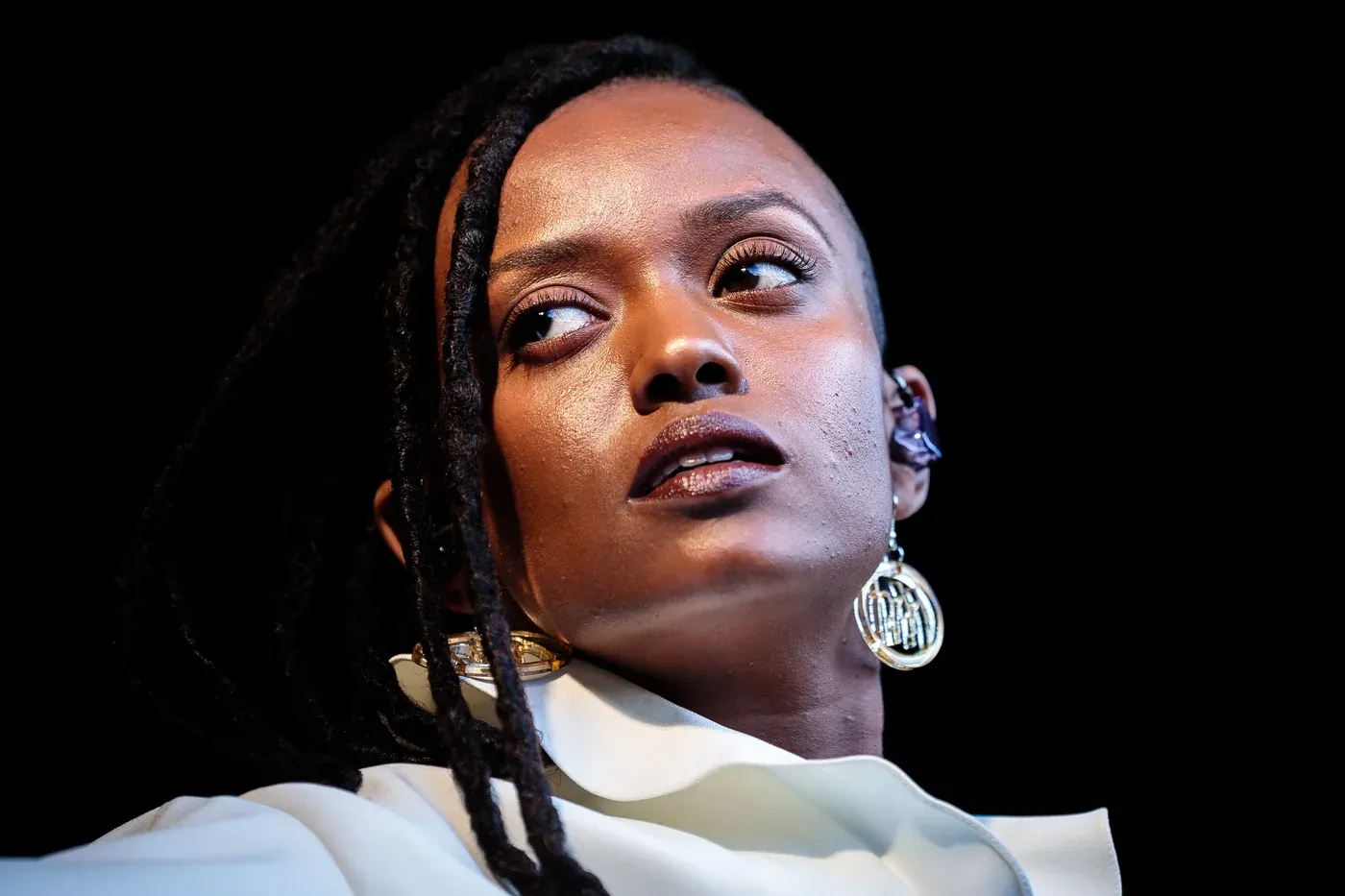 Close-up of Kelela singing on stage with long braids and large silver earrings