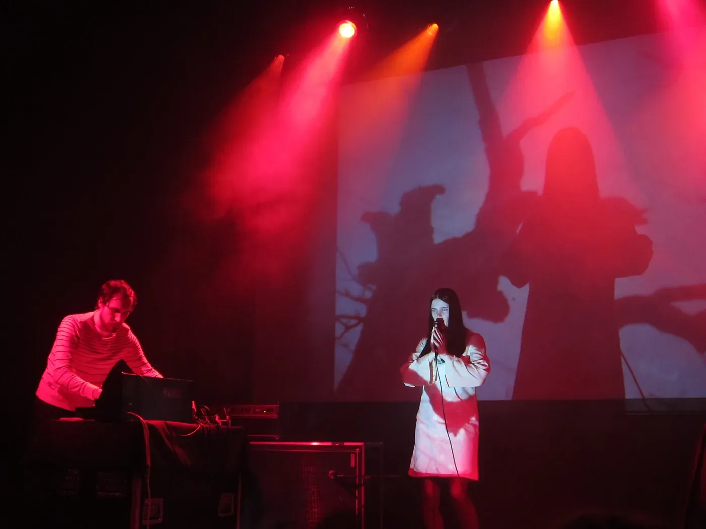 Broadcast performing in red stage light, with Trish Keenan singing at the microphone beside a keyboardist