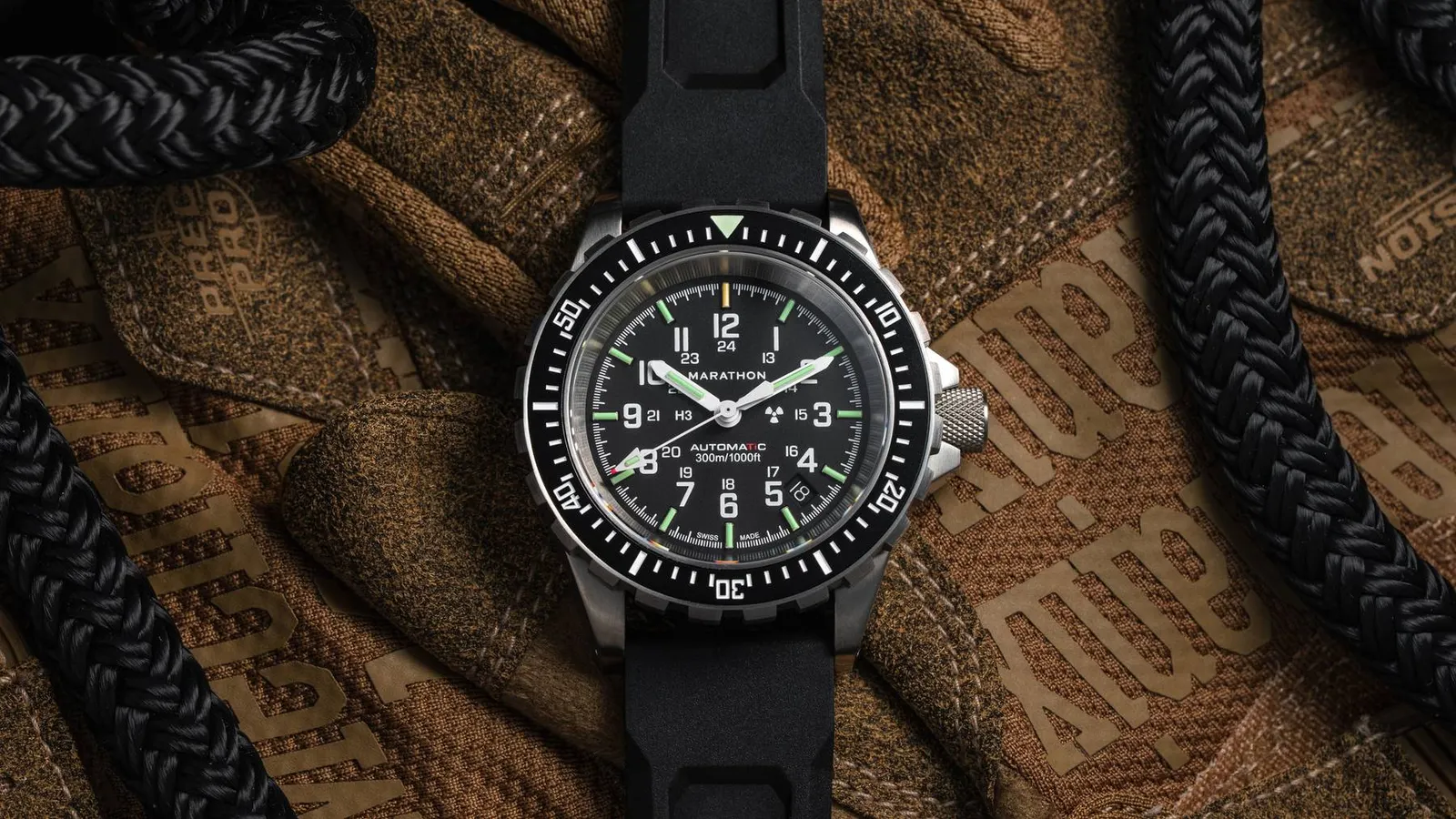 Marathon 41mm Titanium GSAR dive watch with black dial and black rubber strap laid on a tan tactical glove beside black rope