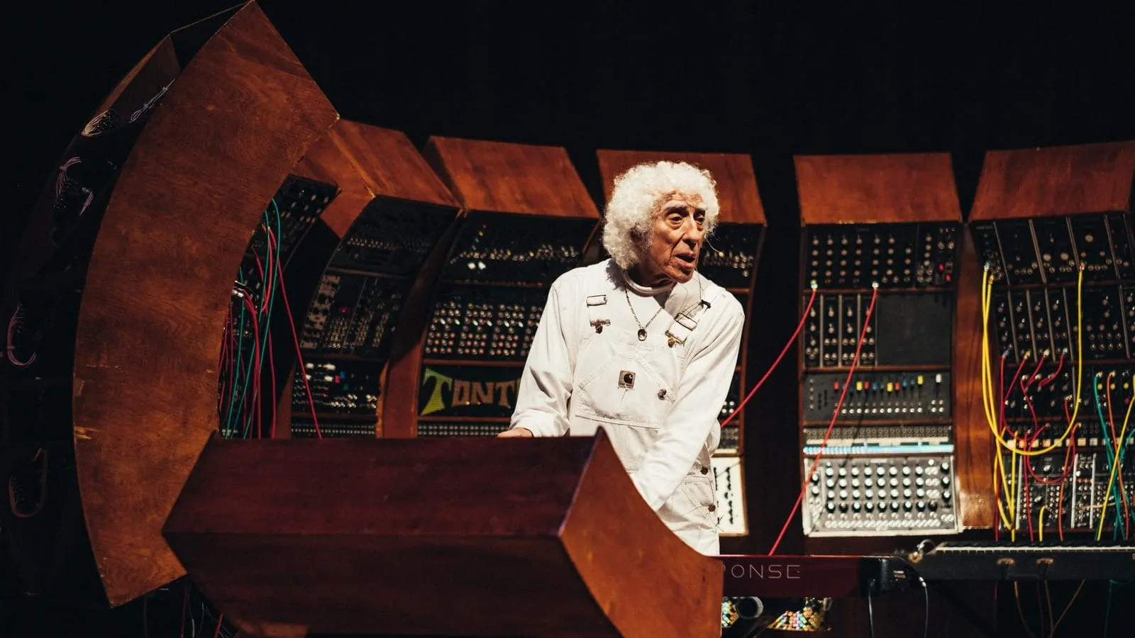 Malcolm Cecil playing TONTO, a wall of Moog and ARP modular synthesizers in curved wooden cabinets strung with patch cables