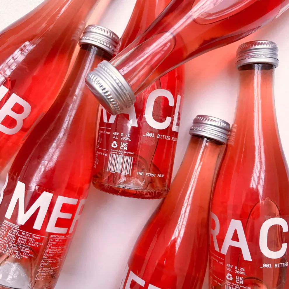Close up of bottles of bright red Club Mera jumbled together against a white background