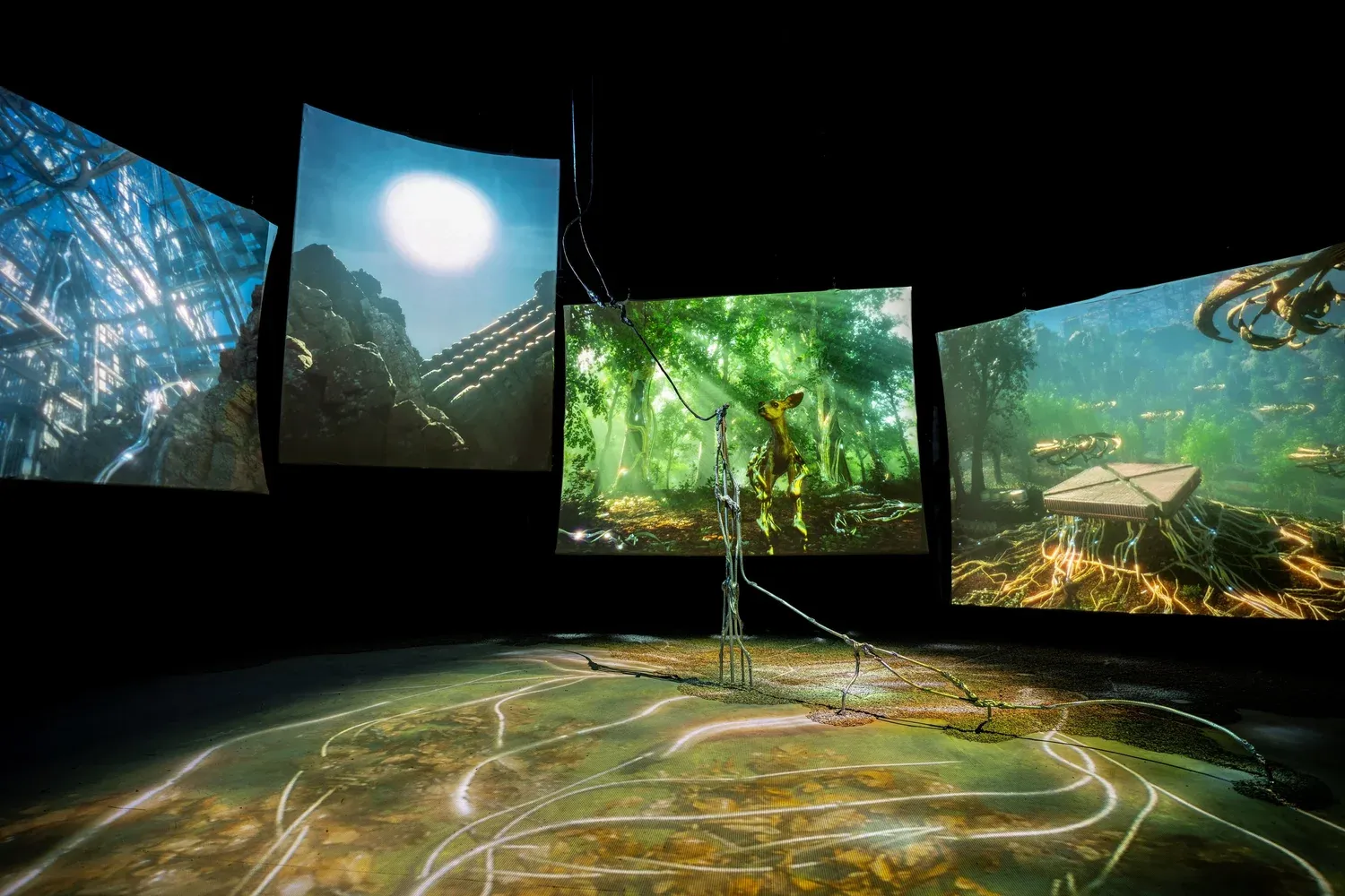 Gallery installation with screens showing a synthetic forest around a metallic tree sculpture