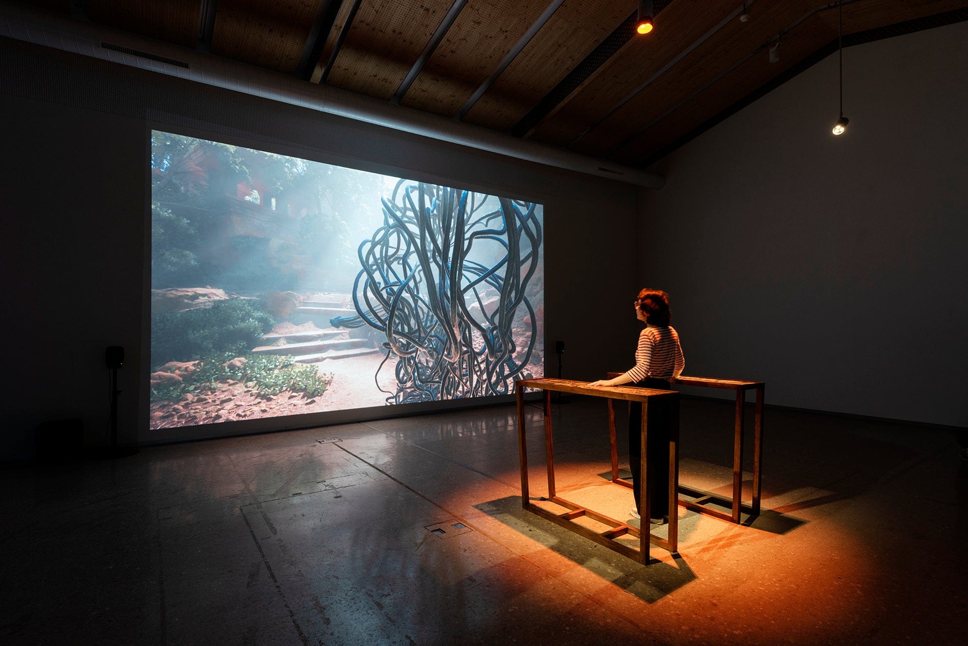 Atithi installed at EPFL Pavilions in Lausanne, with a touch-sensitive brass plate before a large projection