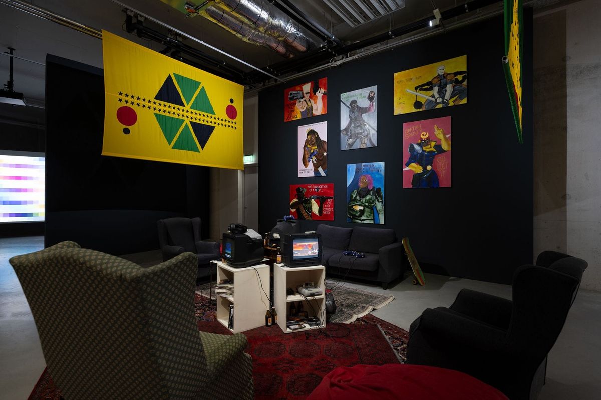 A living room installation with seating and monitors showing video games inside a museum gallery