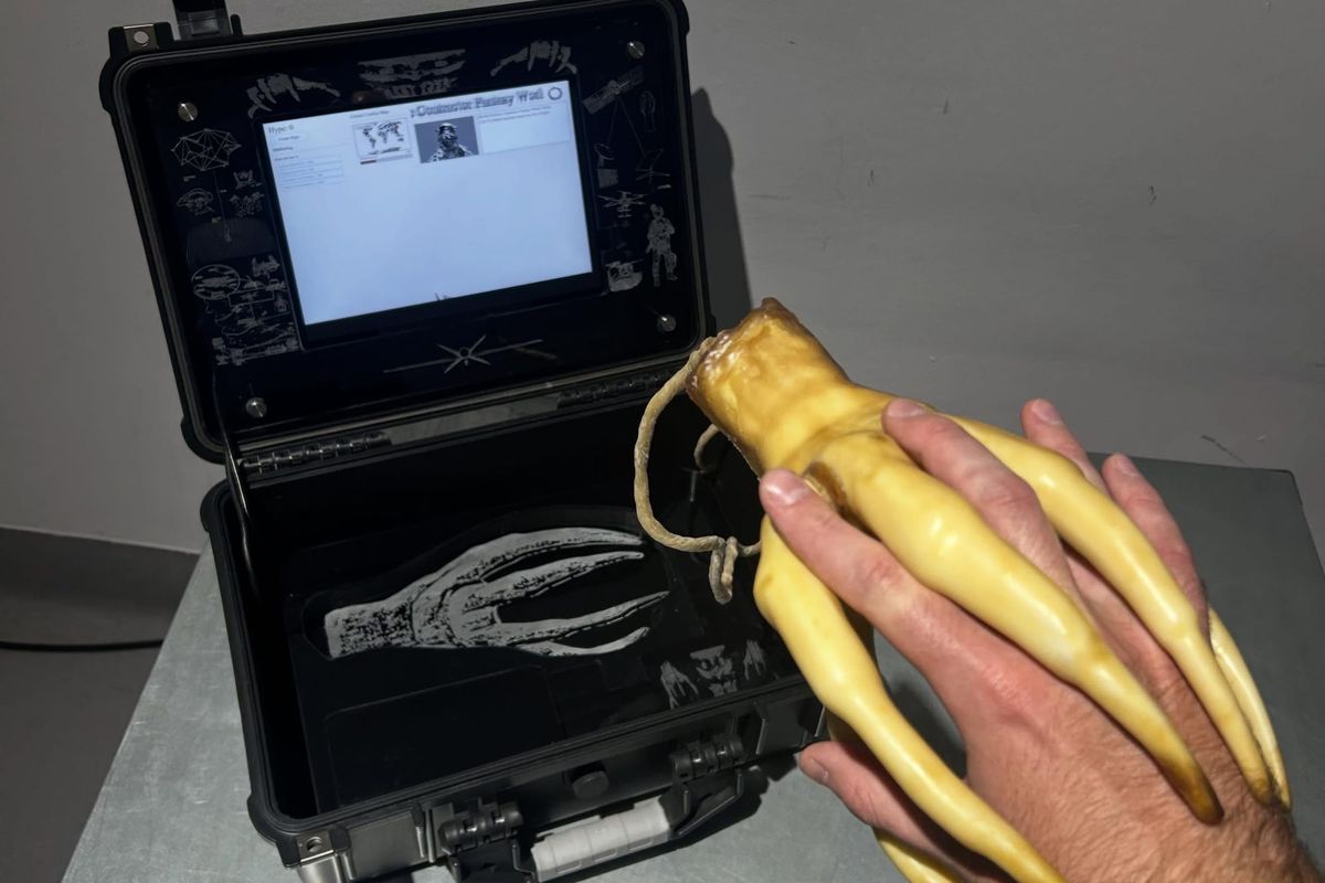 A hand interlocking fingers with the latex demon-hand mouse of Defence Contractor Fantasy World