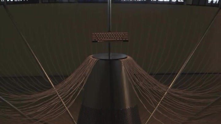 A conical sculpture with wings of mounted phones in a dark gallery