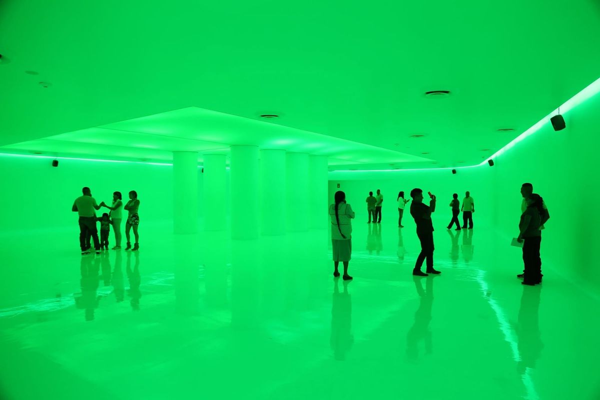 Visitors silhouetted inside the green-lit Espacio Memorial at the Centro de Cultura Digital in Mexico City