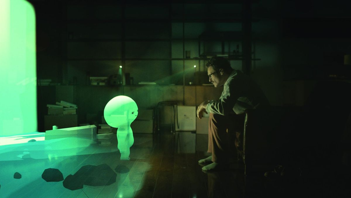 A glowing alien child character projected into a darkened room