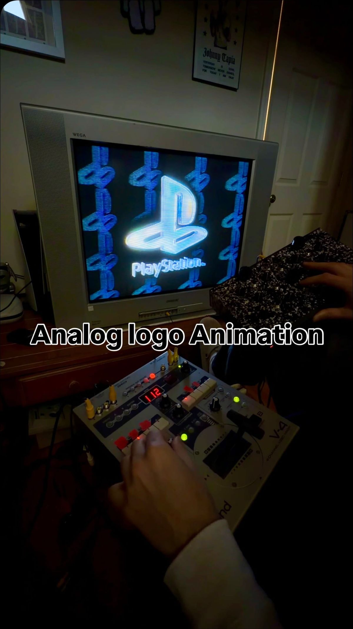 A CRT television on a desk showing a distorted PlayStation logo, surrounded by analog video hardware