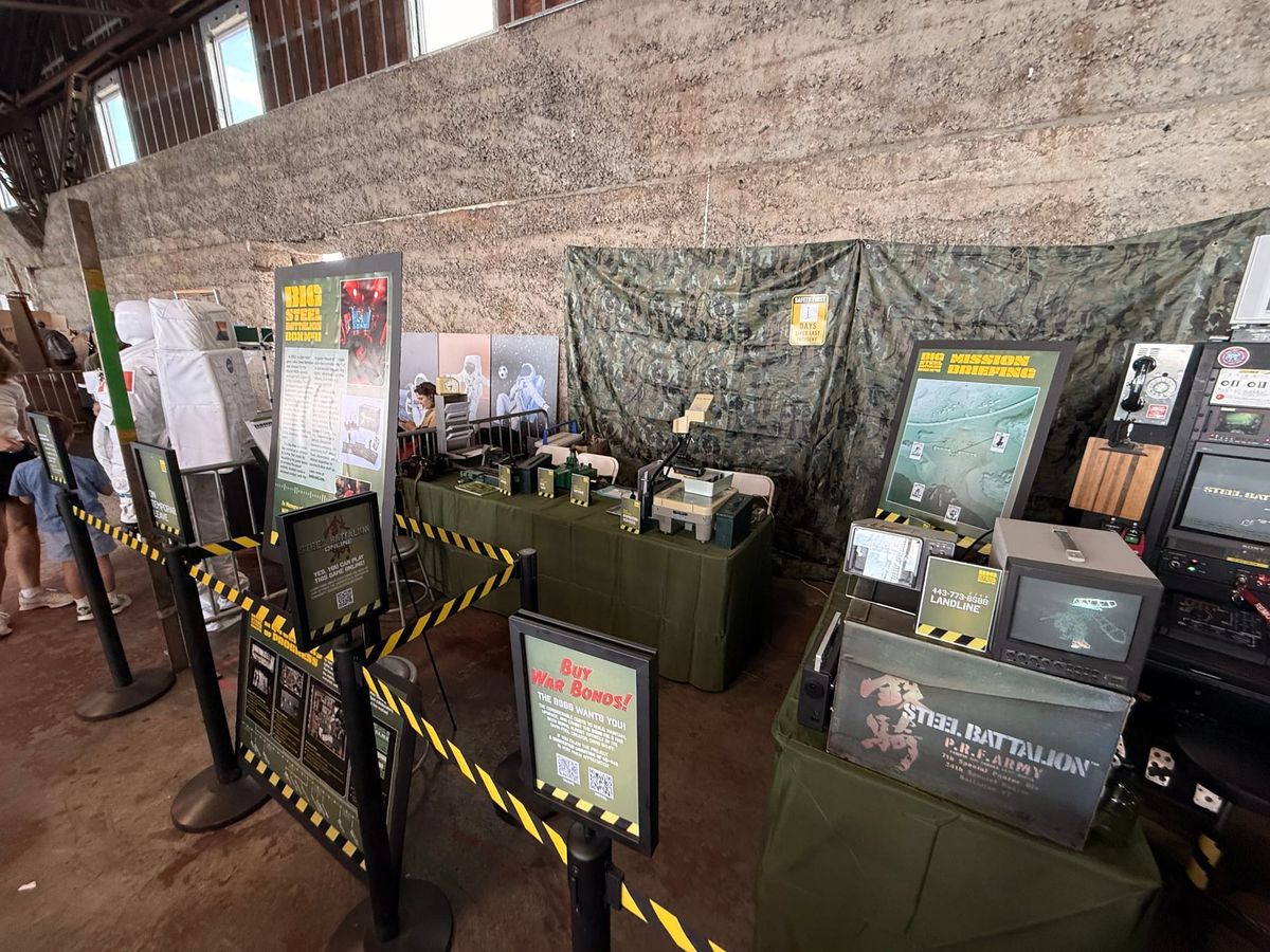 The Big Steel Battalion Box booth at Maker Faire Bay Area 2026, a camouflage-draped cockpit surrounded by monitors and crew stations
