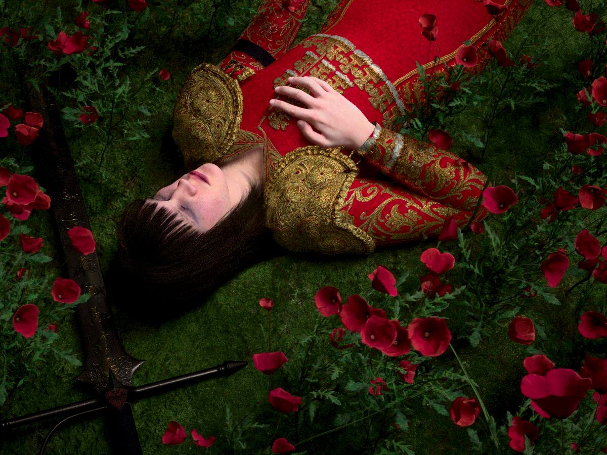 A figure in an embroidered red dress lies in a field of poppies beside a sword in Indulto