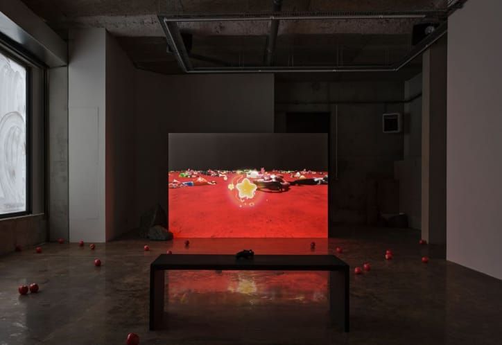 Elouan Le Bars's Side Quest, a glowing red screen installed on a low bench in a dark gallery