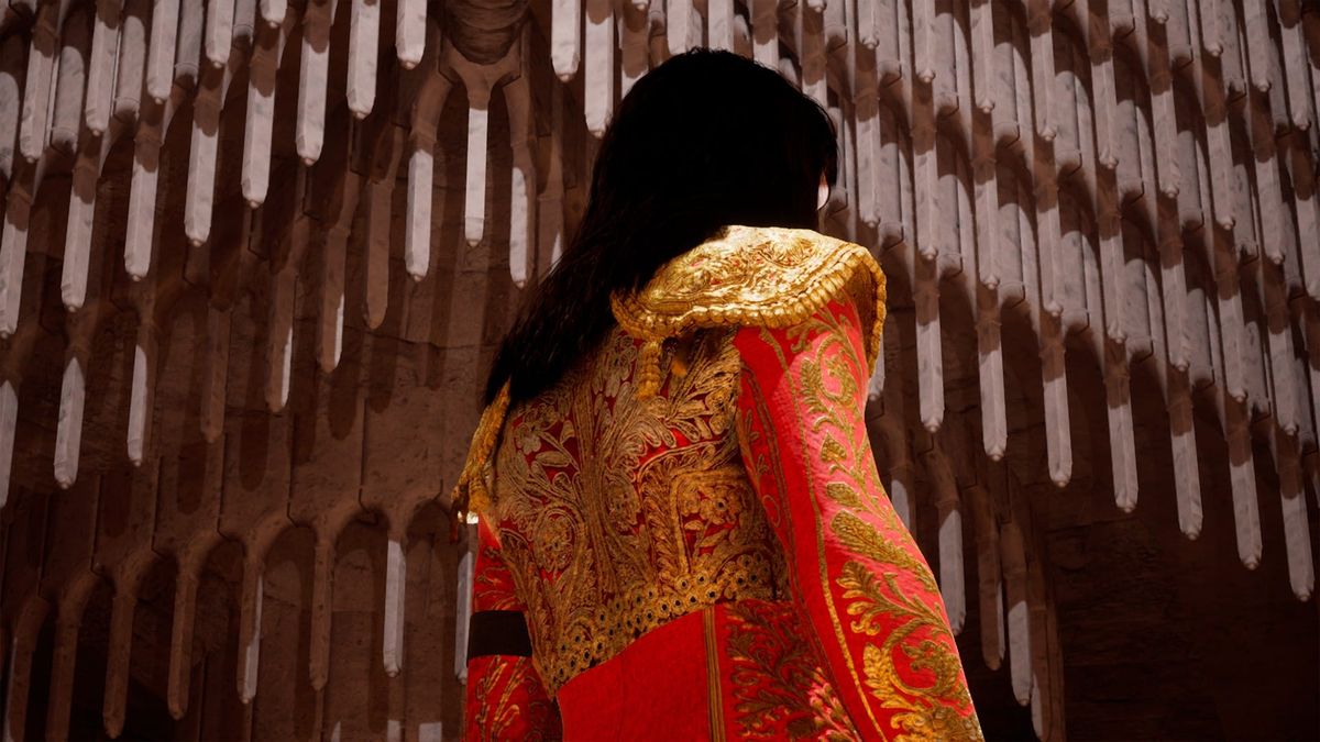 A figure in a red and gold bullfighter's jacket, seen from behind, walking toward the tiered arches of an arena