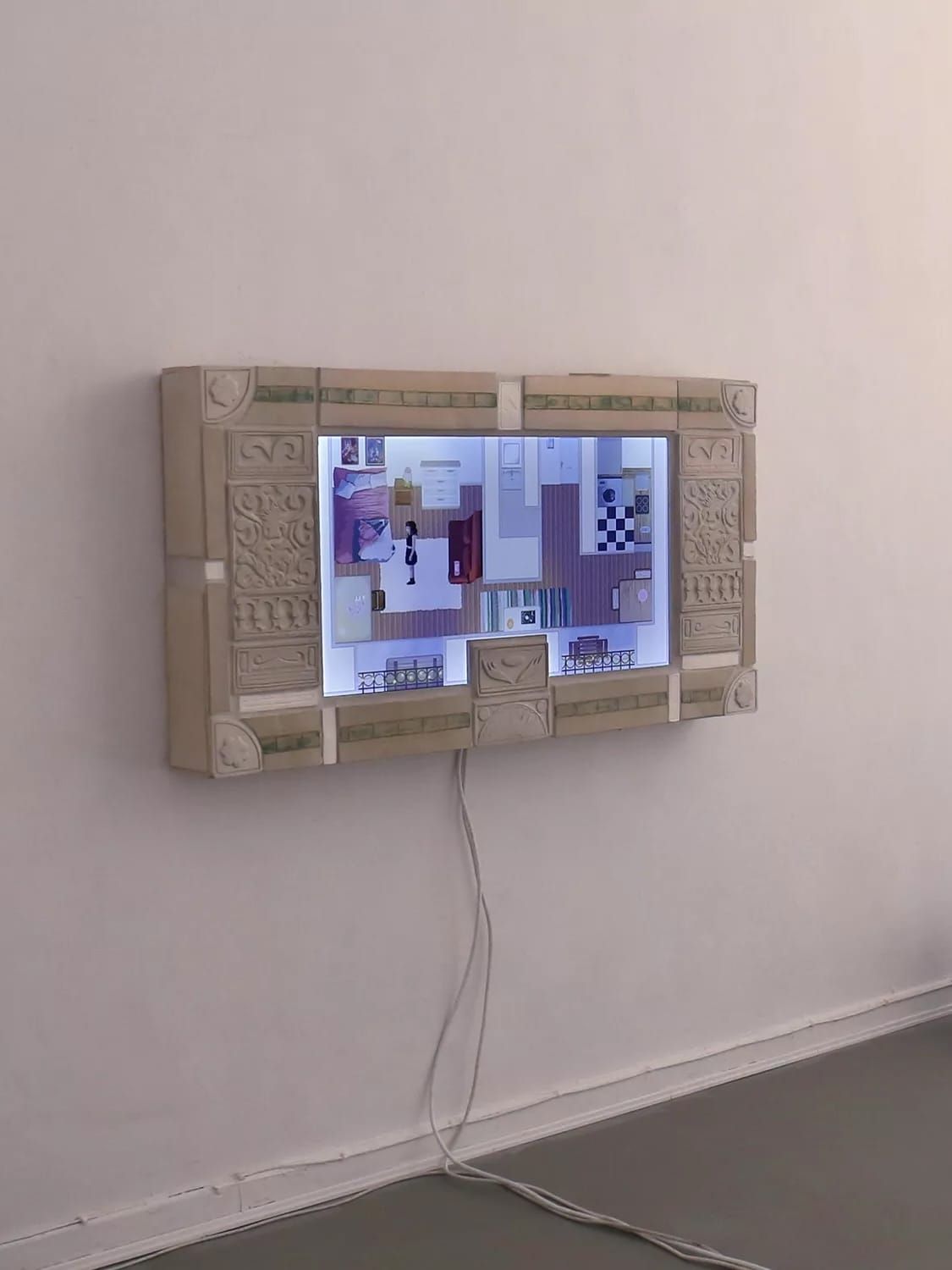 A screen in an ornately molded papier-mache frame mounted on a gallery wall