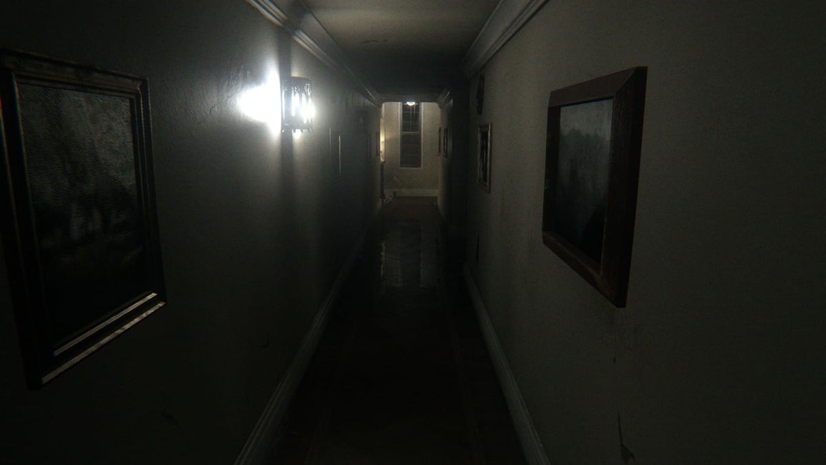 A dim, narrow hallway with framed pictures on both walls and a single bright wall lamp, the corridor from the game P.T.