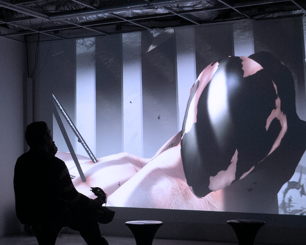 A player holds Aggregate’s custom controller in front of a large projection