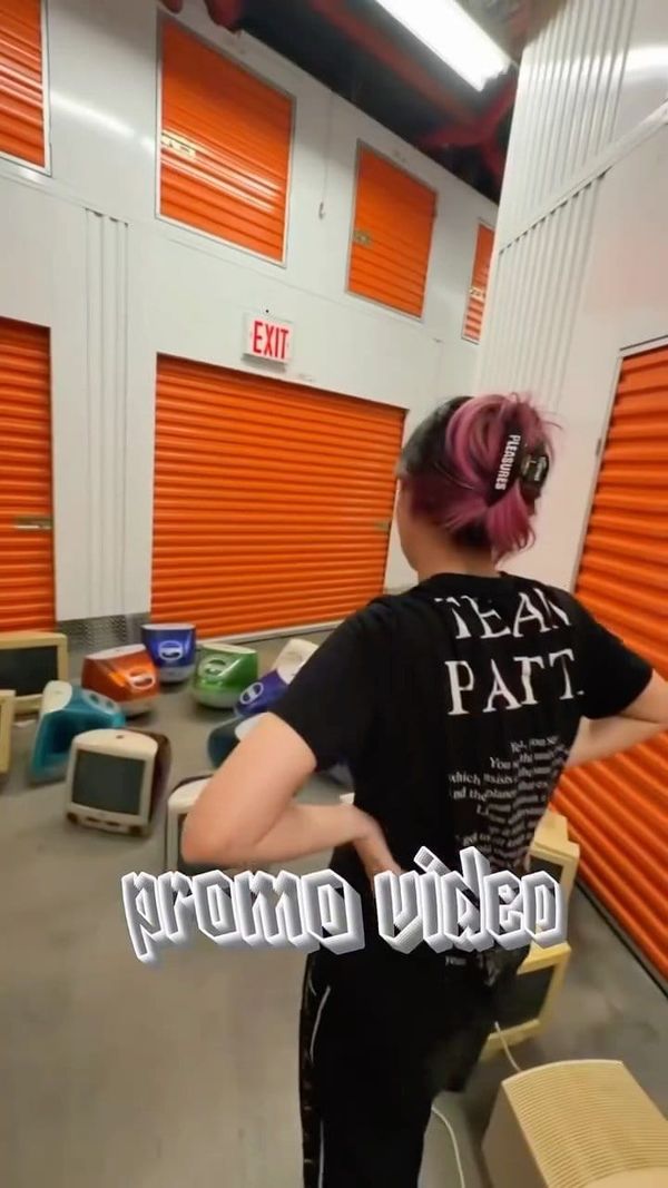 Paizley Lee stands in a storage unit surrounded by candy-colored iMac G3 computers