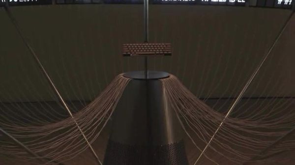 A conical sculpture with wings of mounted phones in a dark gallery