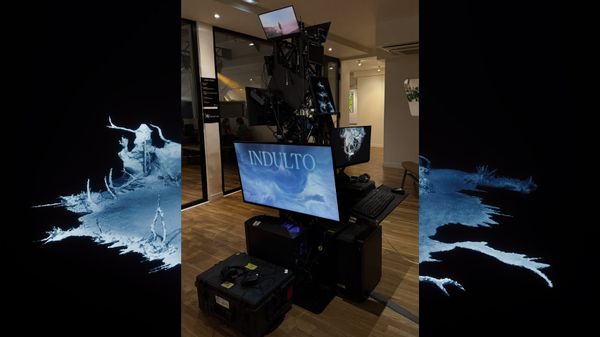 A stacked tower of screens and road cases displays video games inside a gallery space.