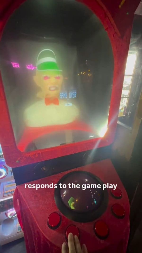 A red arcade cabinet with an animatronic fortune-teller head behind glass, trackball and red buttons