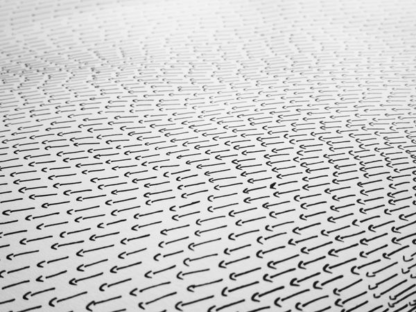 A dense grey field of small repeated marks receding in perspective, like a surface of sound waves seen at an angle.