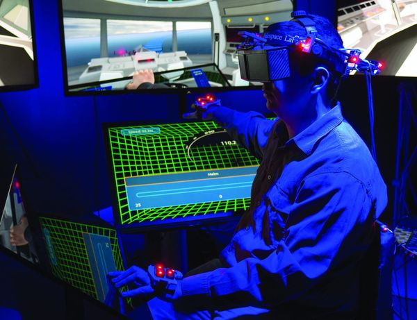 A researcher in a blue lit lab wearing a tracked head-mounted display
