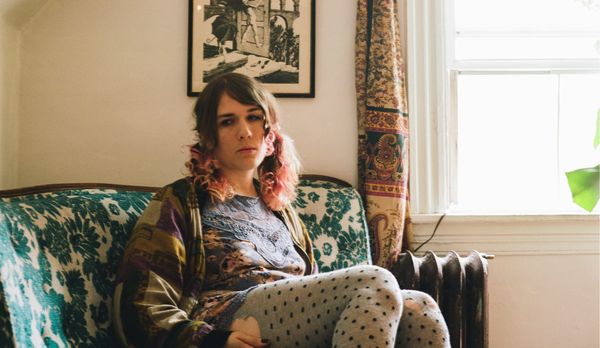 Lily Zone sitting on a patterned green couch in a sunlit living room