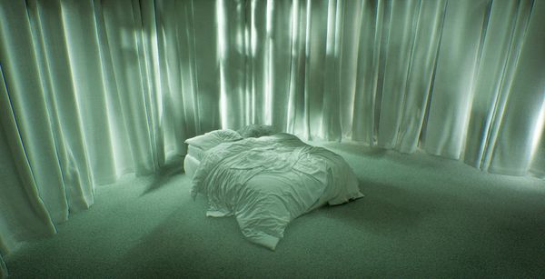 A pale green room with a single unmade bed under hanging curtains, from Pierre Moulin's VR film After the Shell