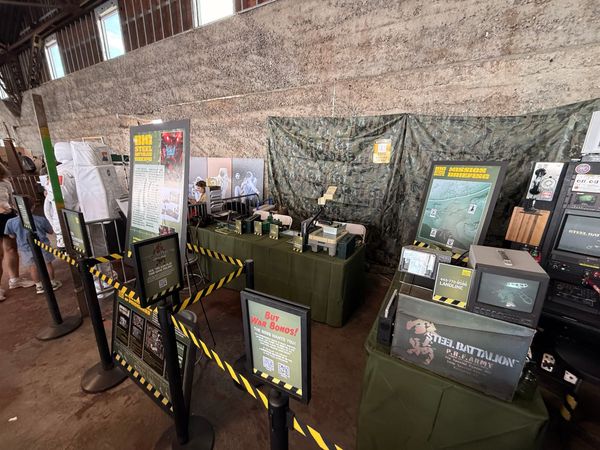 The Big Steel Battalion Box booth at Maker Faire Bay Area 2026, a camouflage-draped cockpit surrounded by monitors and crew stations