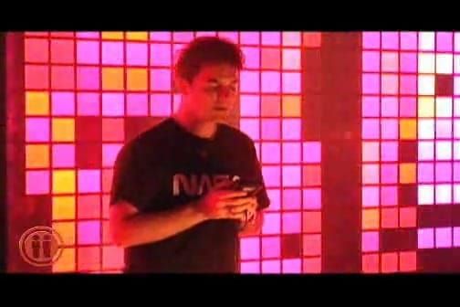 Nullsleep performing in front of a wall of glowing pink and magenta squares