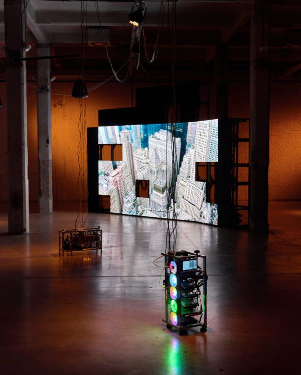 A gallery with a large LED screen showing an aerial city view, a crypto mining rig glowing in front of it
