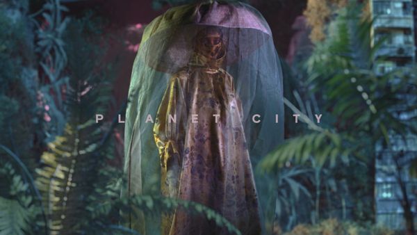 A figure in a translucent veil and elaborate costume stands among dense jungle plants, with the words Planet City across the frame
