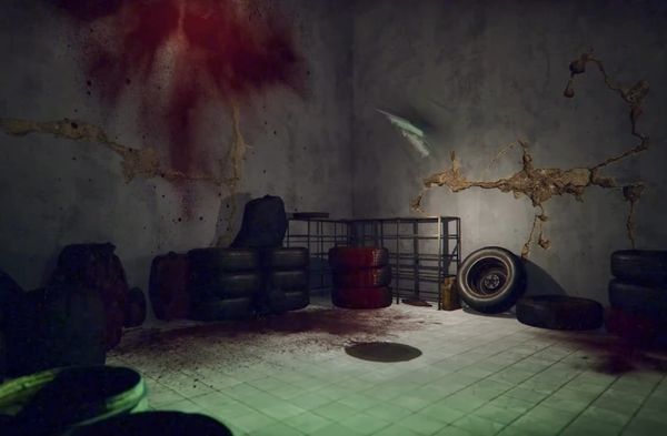 A concrete room of stacked tires and shelving under a red smear on the wall, lit green from below