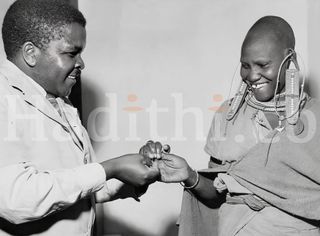 A smiling Masai girl allows a dresser at the Native Hospital at Kajiado to blood slide