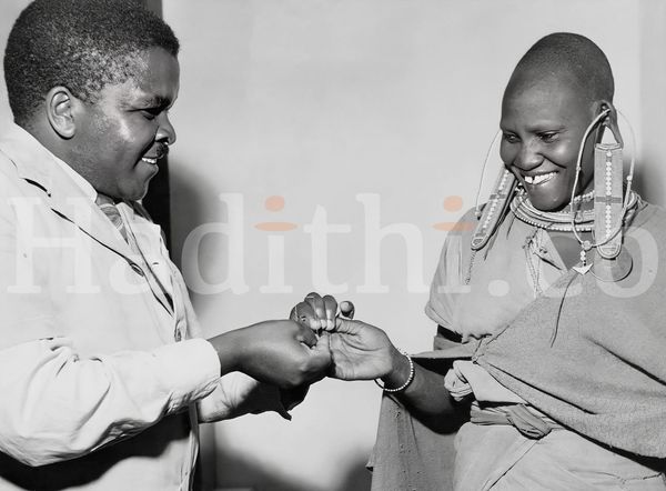 A smiling Masai girl allows a dresser at the Native Hospital at Kajiado to blood slide